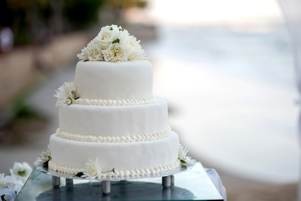 3 layered traditional white wedding cake with blur background