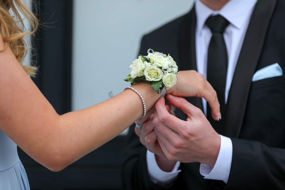A corsage being placed on a bridesmaid's wrist on wedding day
