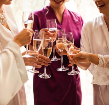 Bride and bridesmaids celebrate and drinking champagne