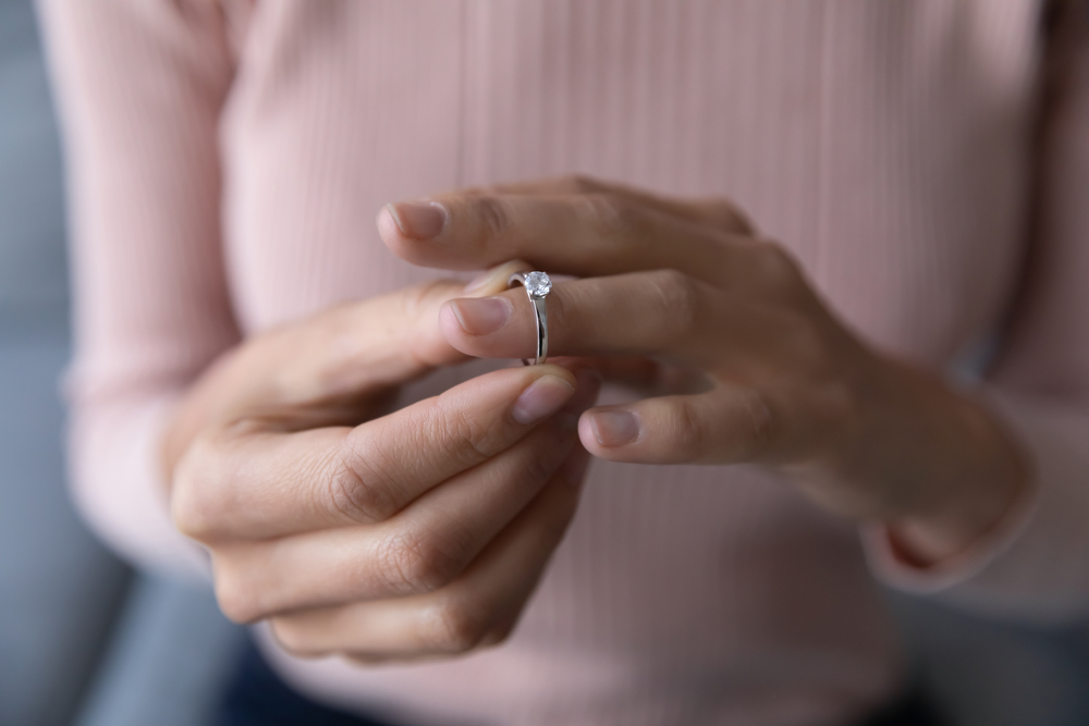 Close up young woman taking off wedding ring because of annulment