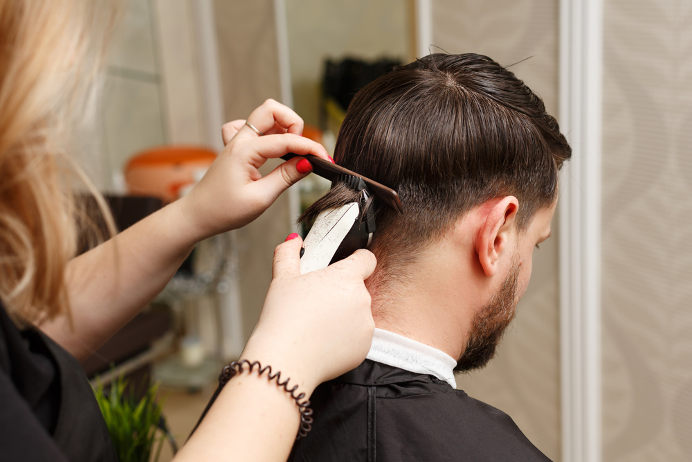 Professional hairdresser doing haircut man's hair