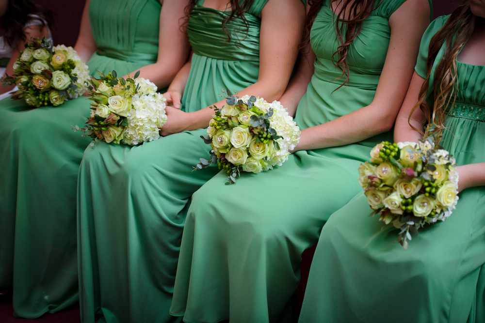 Row of sitting bridesmaids with bouquets at wedding ceremony