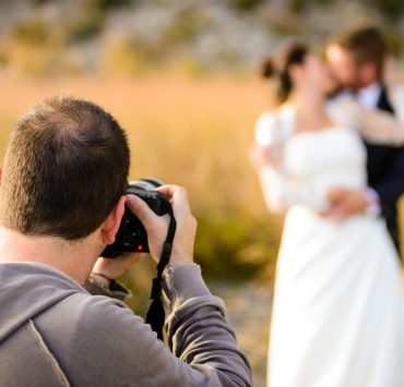 Wedding photographer taking photographs of groom and bride