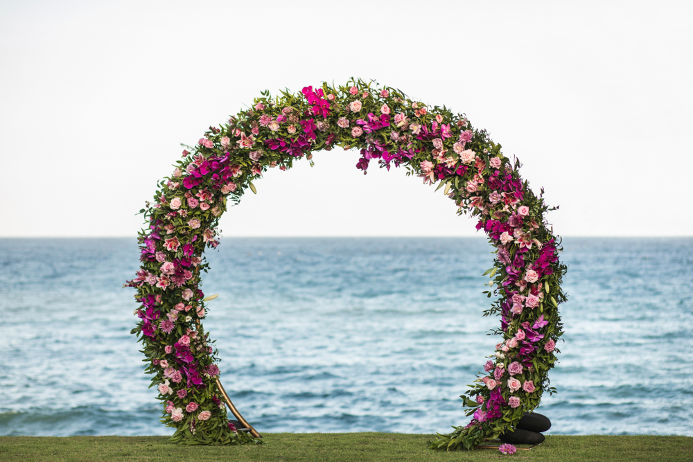 Wedding round arch decorated with beautiful colorful orchid and rose flowers on the beach