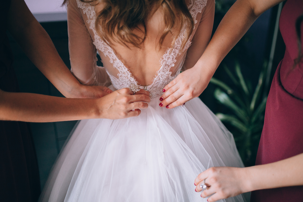 hands helping with bride's white corset