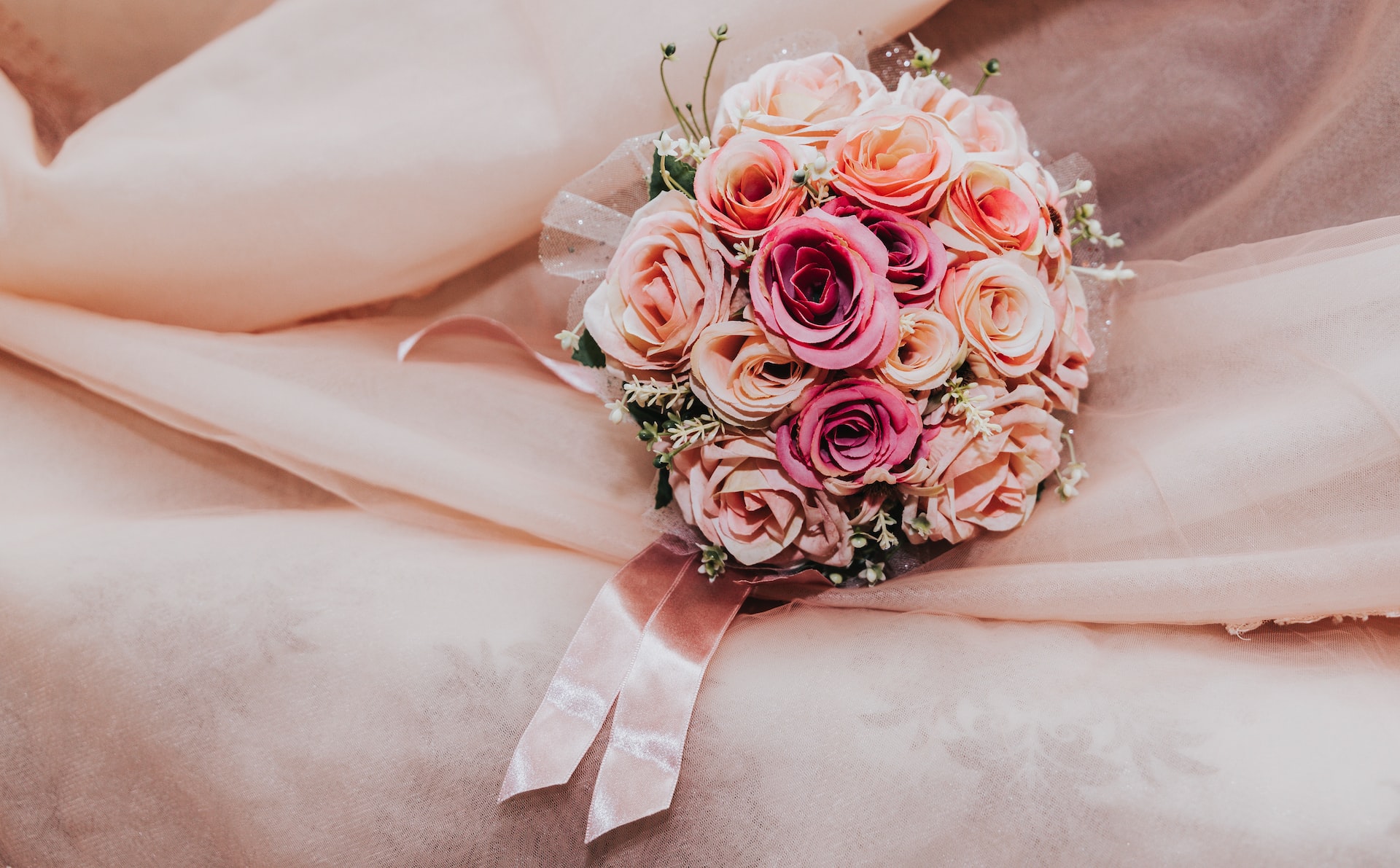 wedding bouquet of pink roses with ribbon on pink cloth