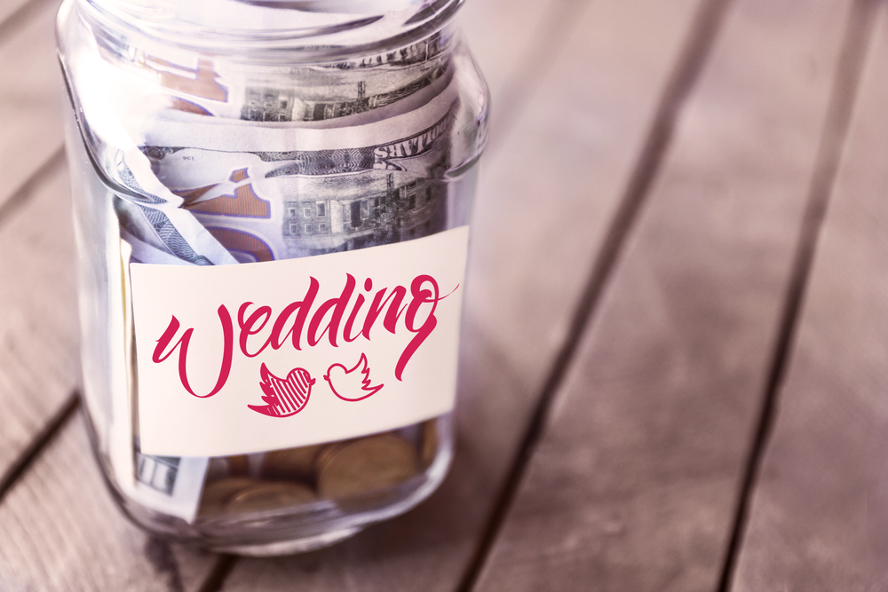 wedding savings in glass bank on wooden table