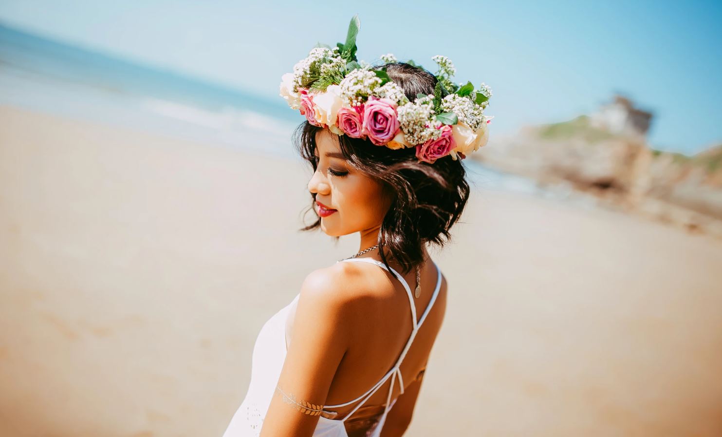 woman wearing white halter dress and floral tiara