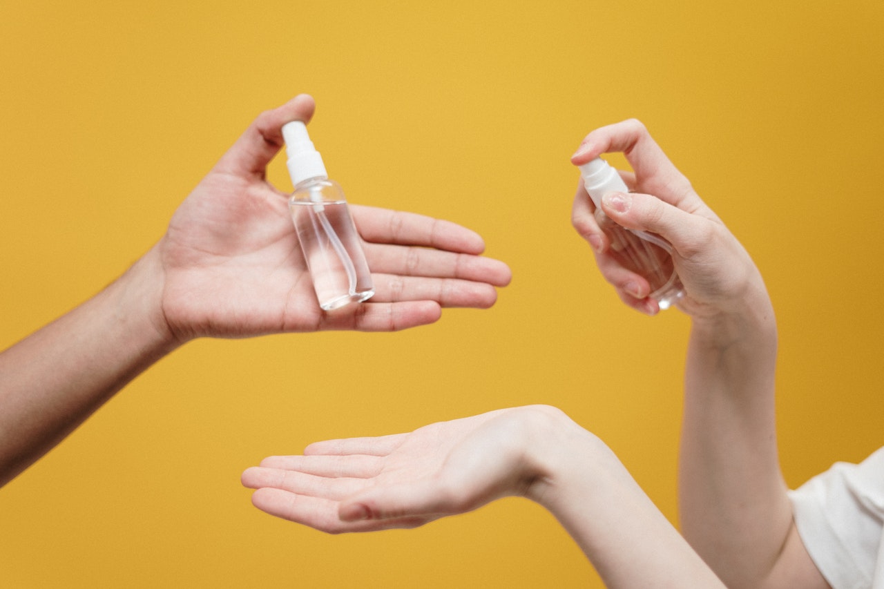 hands holding hand sanitizer bottles