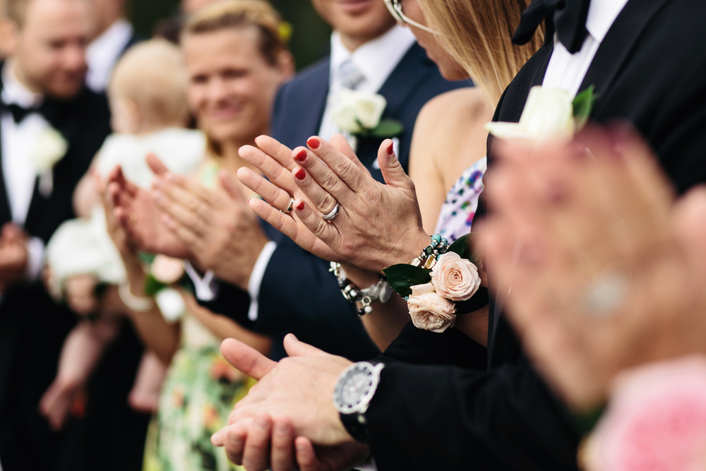 A closeup of the palms of wedding guests while they applauding