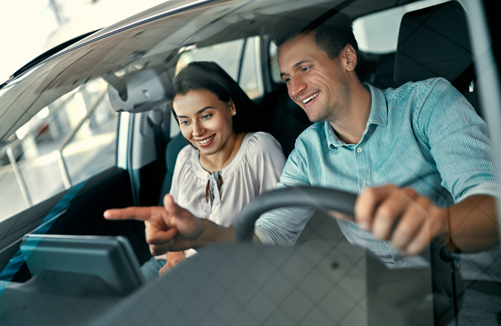 A young couple in a car while looking at the maps on table