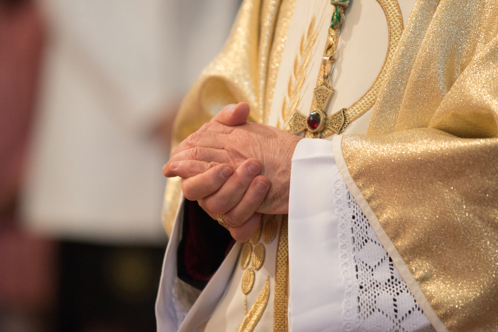 Catholic priest holding his hands in church