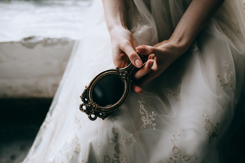 bride holds a vintage hand mirror