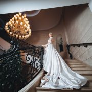 bride in a white long dress climbs up the stairs in a classic interior