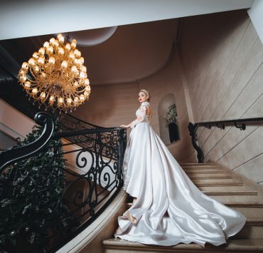 bride in a white long dress climbs up the stairs in a classic interior