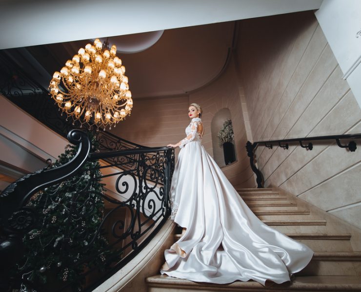 bride in a white long dress climbs up the stairs in a classic interior