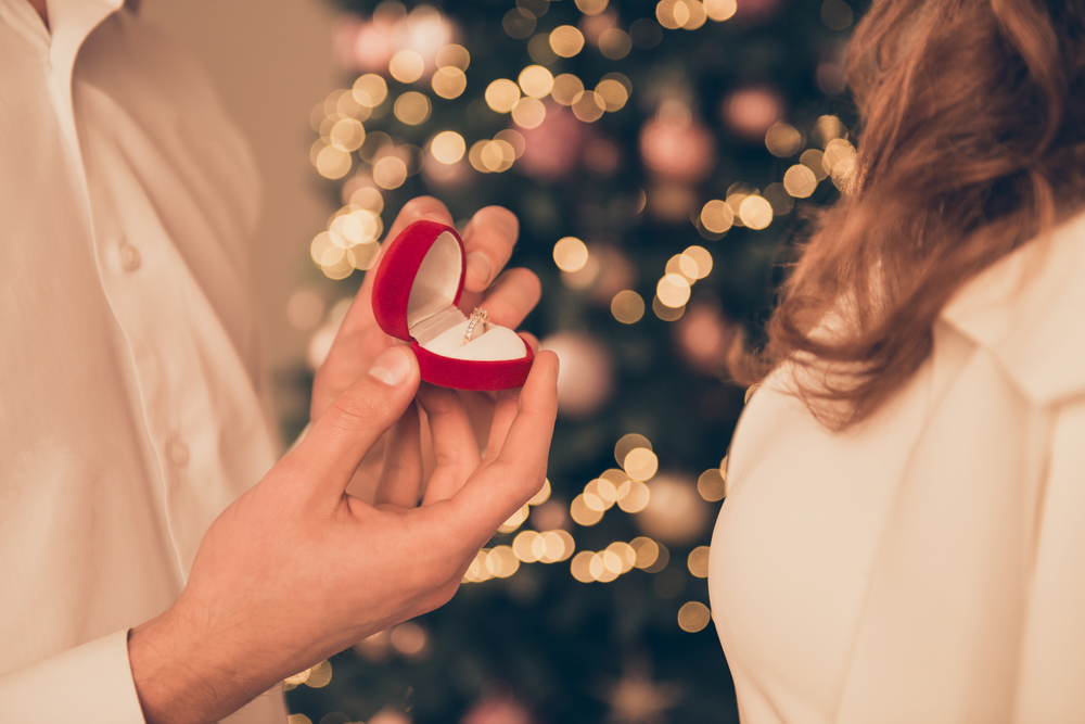 man proposes next to a christmas tree