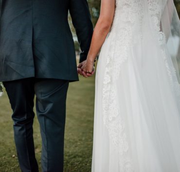 young couple holding hands newlyweds in the field