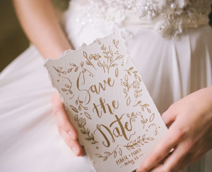 close up of Save The Date card on bride's hands