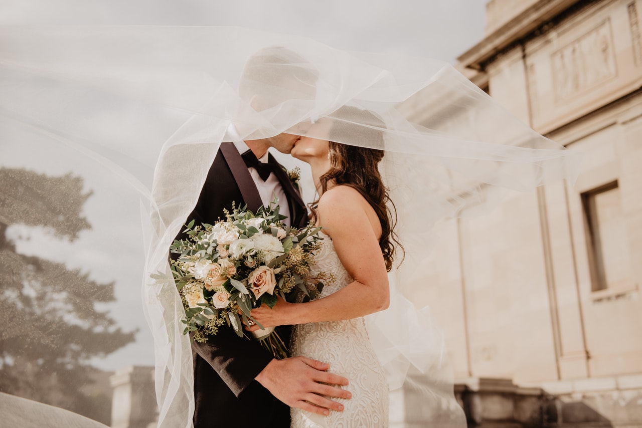 a newlywed couple shares a romantic kiss outside the church