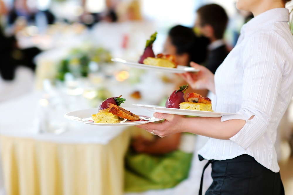 a server at a wedding reception with plates of food