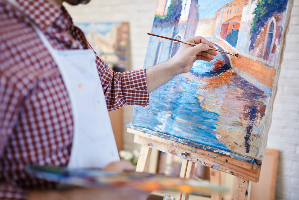 Hand of artist painting Italian landscape