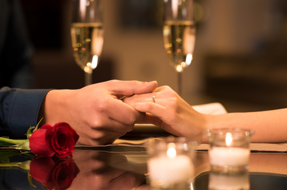 couple holding hands while having their candlelit dinner
