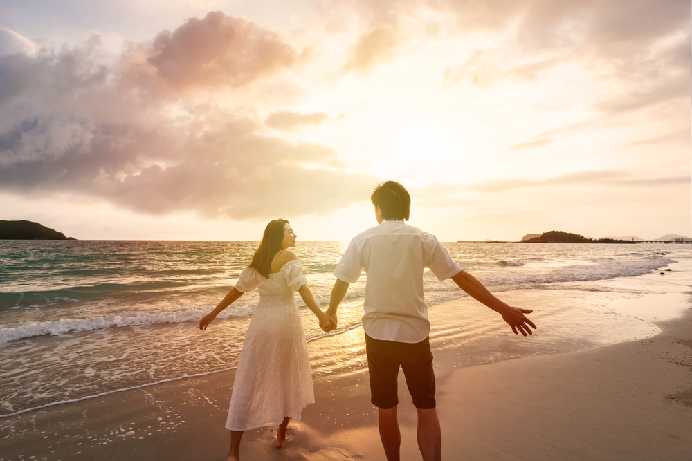 couple holding hands while walking in the beach