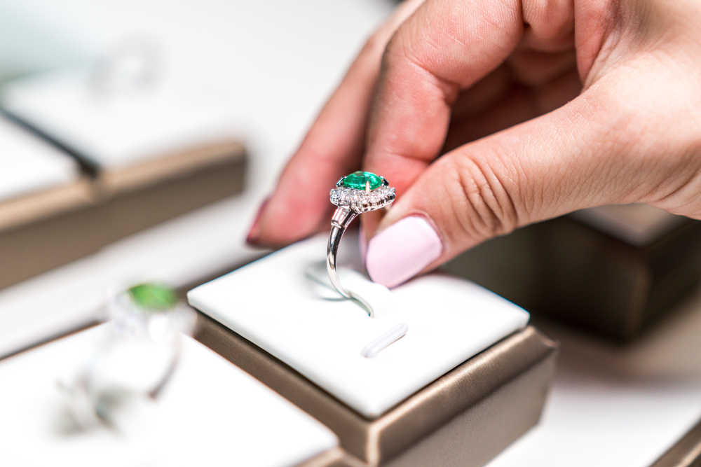 hand picking up a wedding emerald ring in a box