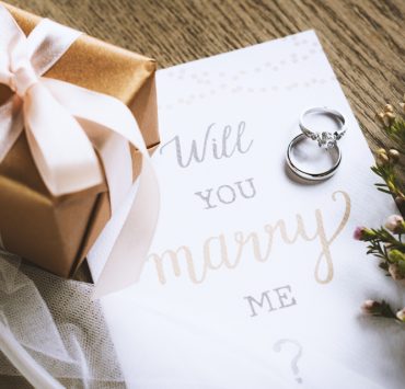 will you marry me note with a gift and flowers on the side
