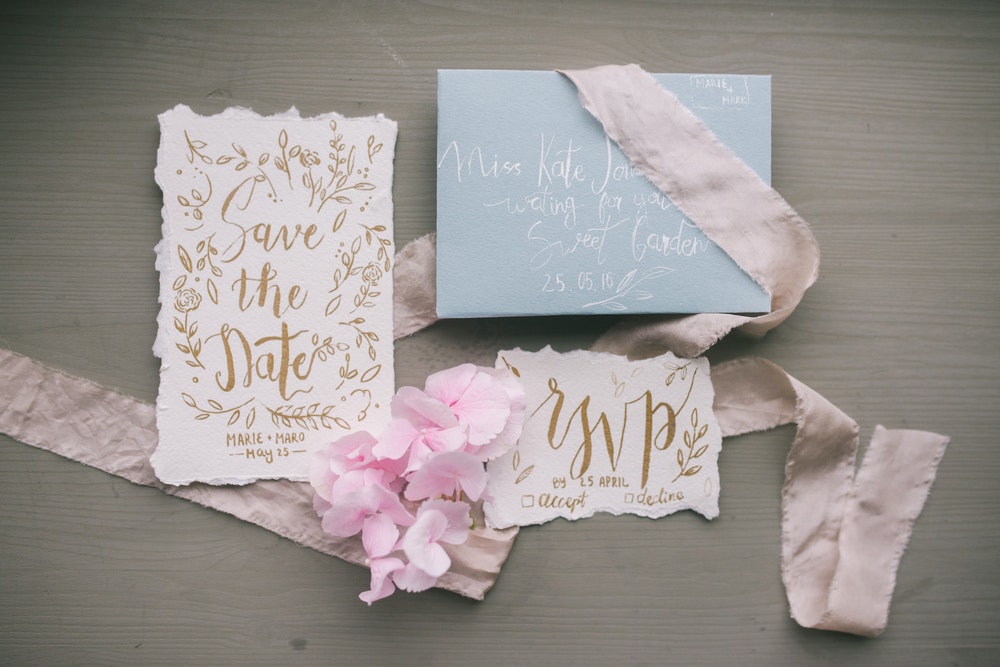calligraphy wedding invitation and save-the-dates on wooden table