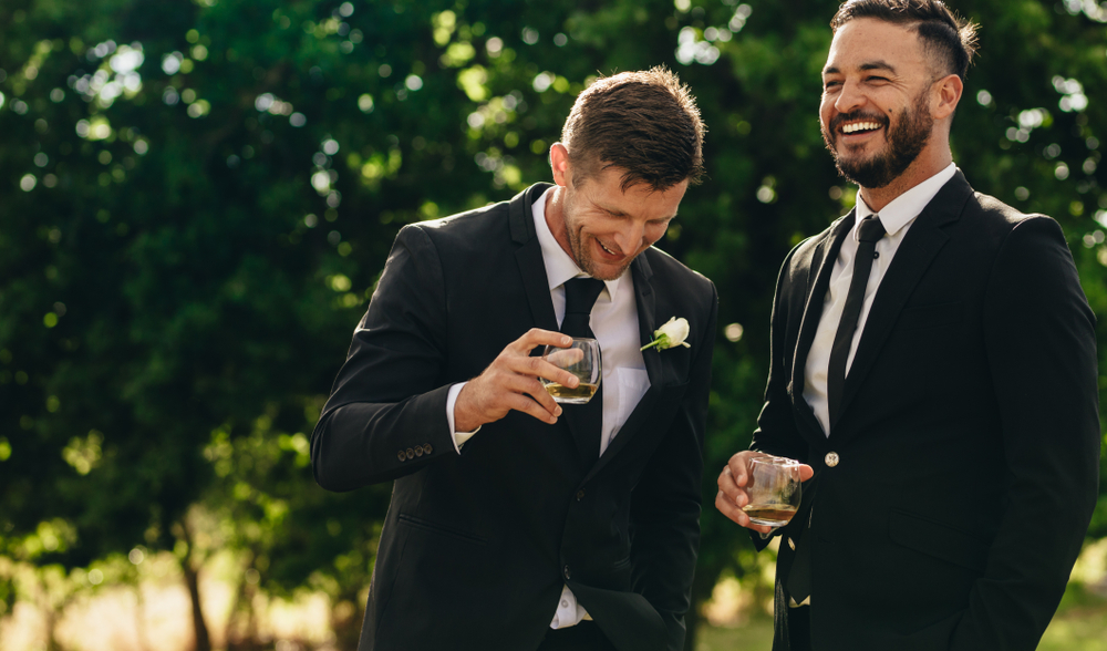 groom and his best man laughing together while drinking alcohol