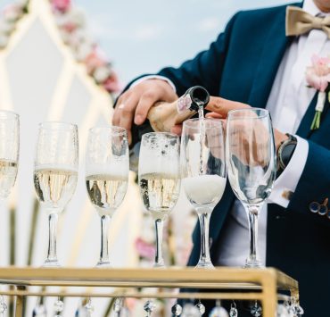 groom pouring champagne on glasses