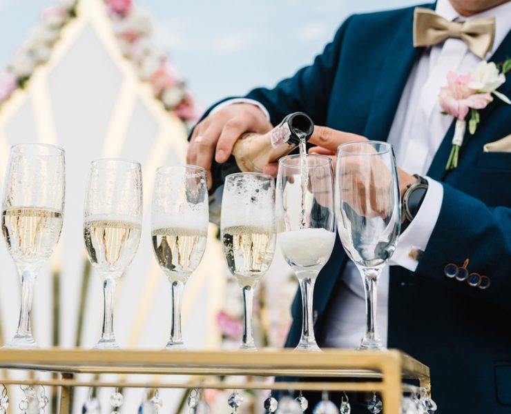 groom pouring champagne on glasses