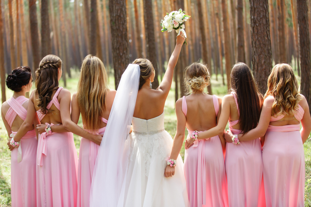 bride and her bridesmaids with their backs turned away from the camera