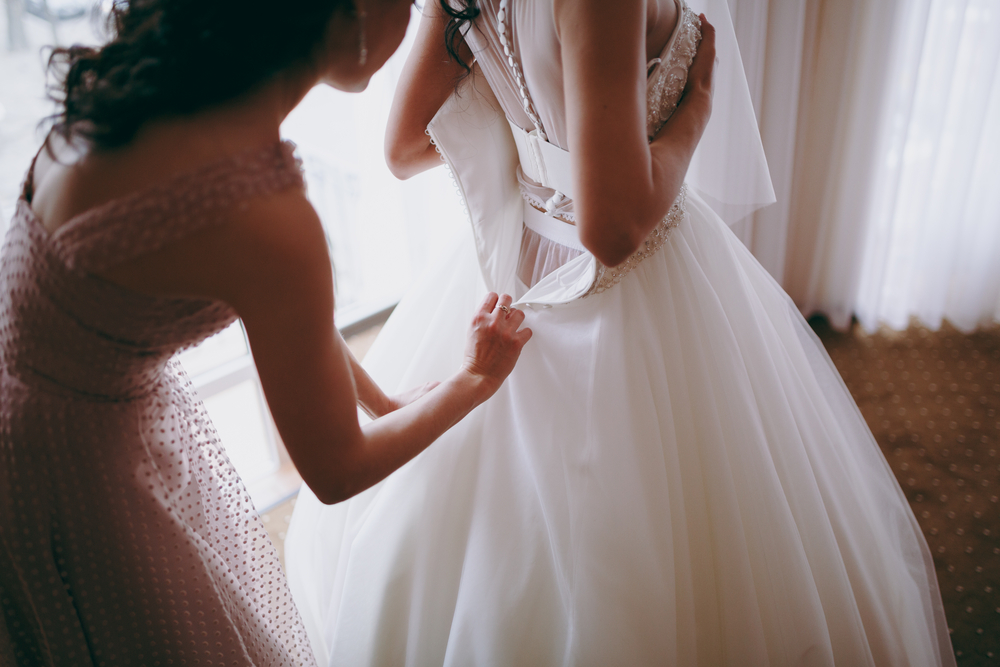 bridesmaid helping remove a layer of the bride's gown