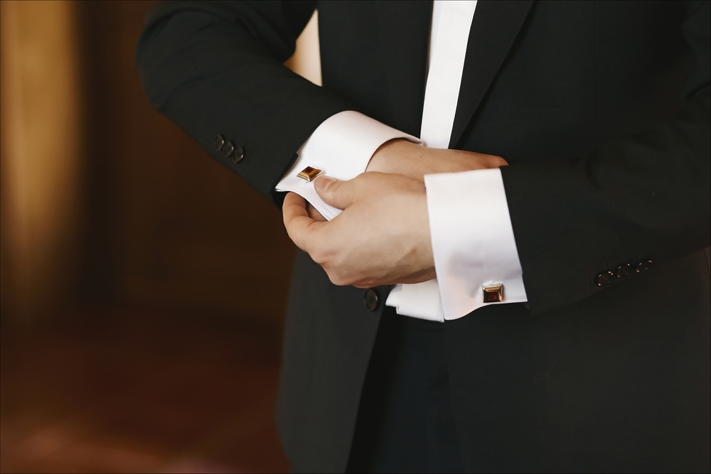 groom buttoning his tuxedo's cufflinks