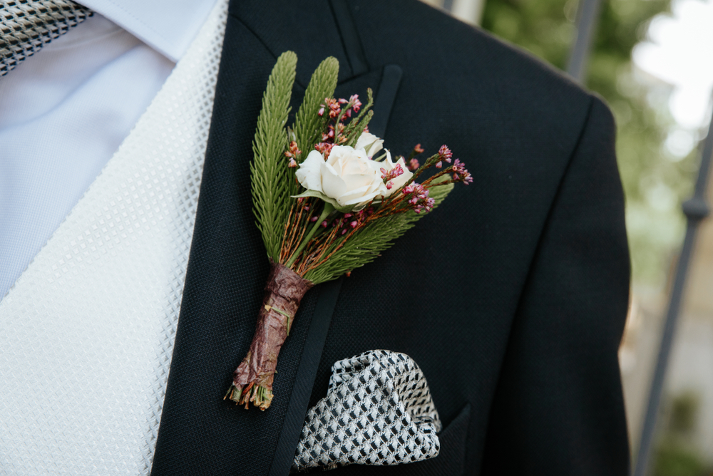 groom's boutonniere with a rose and sprig of fir for a rustic themed wedding