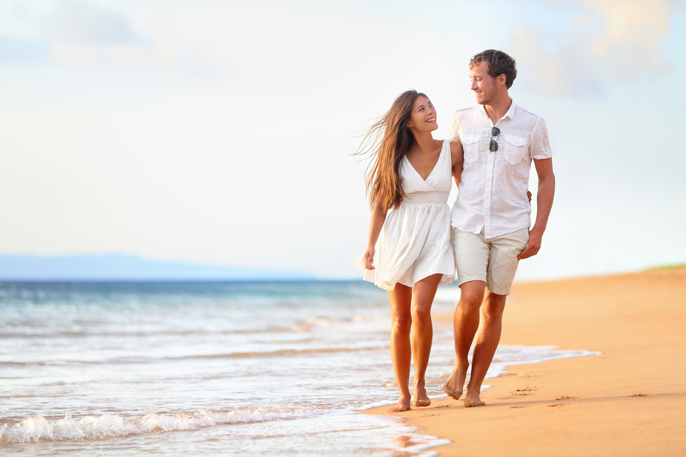 a couple walking on the beach during daylight