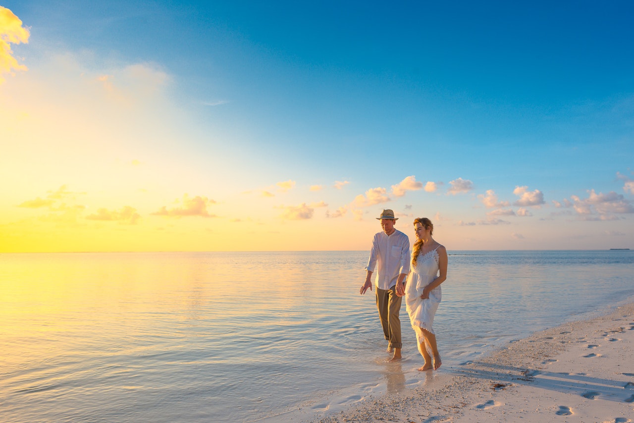 married couple walking on the beach shore