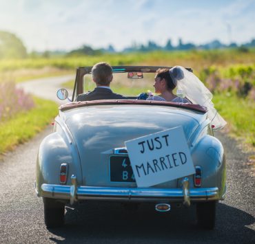 Newly wed riding a car on the way to their honeymoon destination