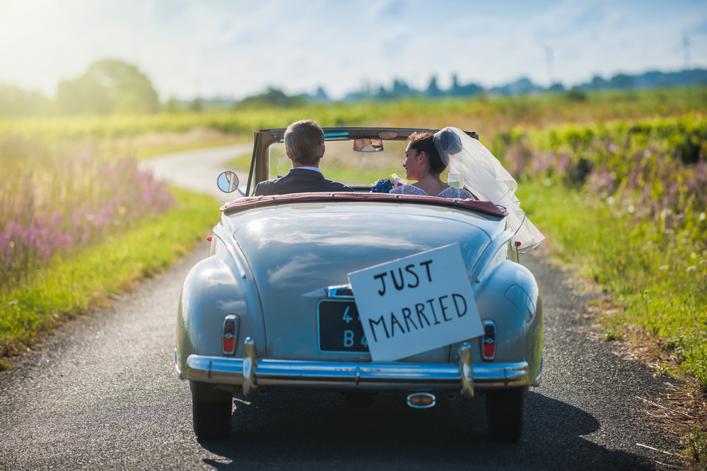 Newly wed riding a car on the way to their honeymoon destination