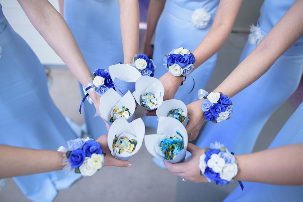 Bridesmaids with flower wrist corsages holding rose petals at a blue theme wedding
