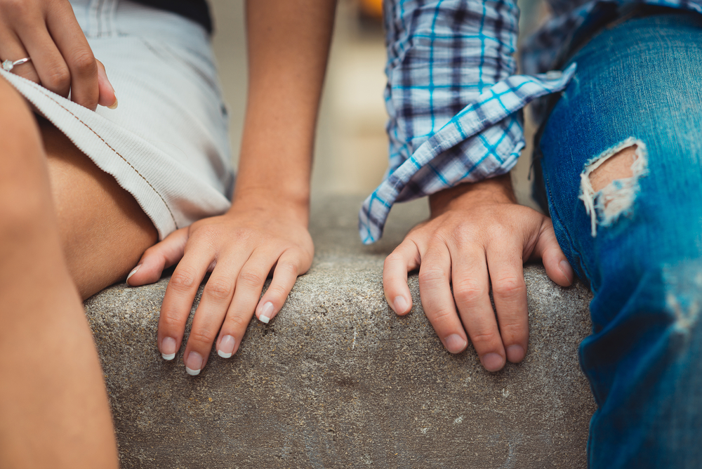 Hands of young couple in love close side by side on the first date