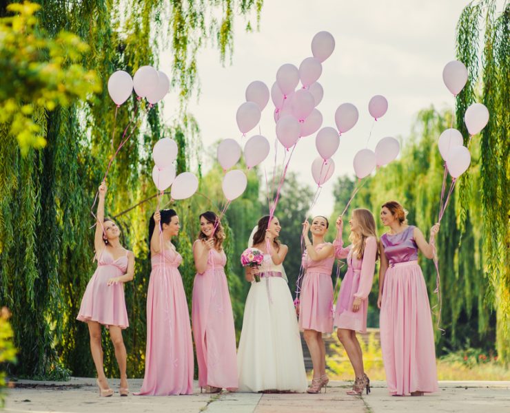 Happy bride and bridesmaids holding pink balloons