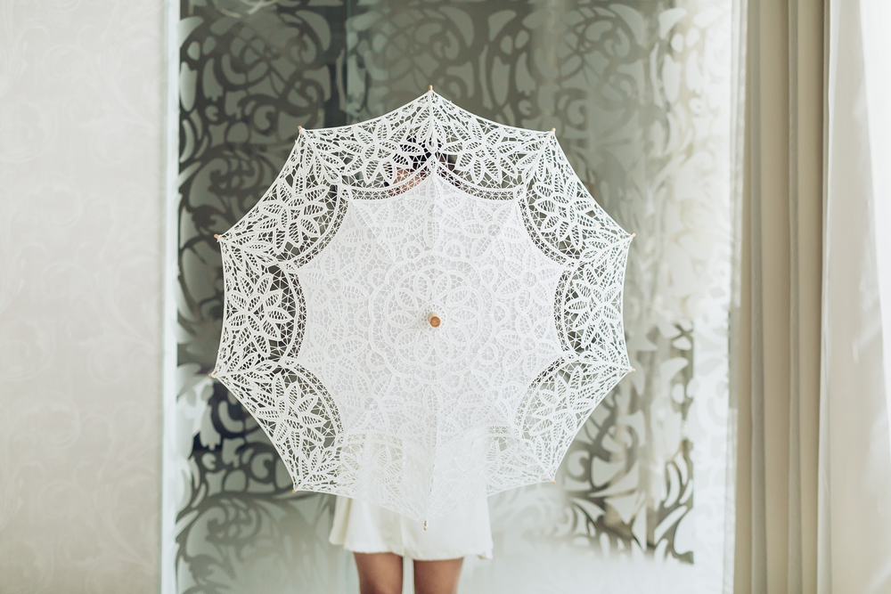 a bridesmaid hiding behind a white fabric parasol