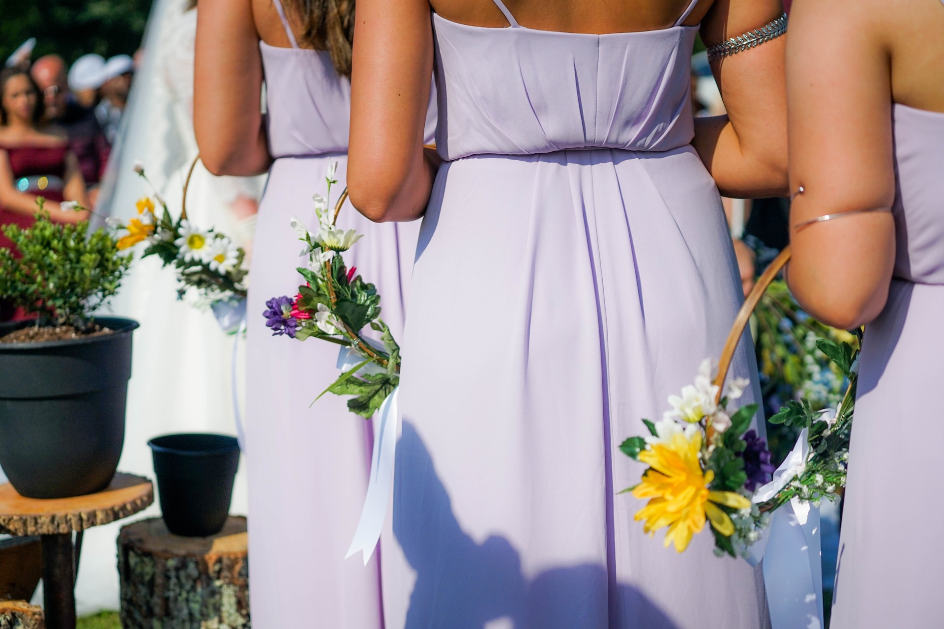 back view of bridesmaids on purple dresses walking while carrying hoop bouquets