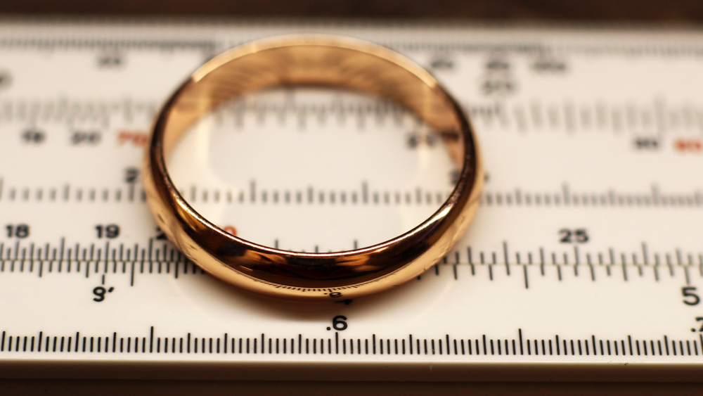 a gold wedding ring on top of ring measuring instrument