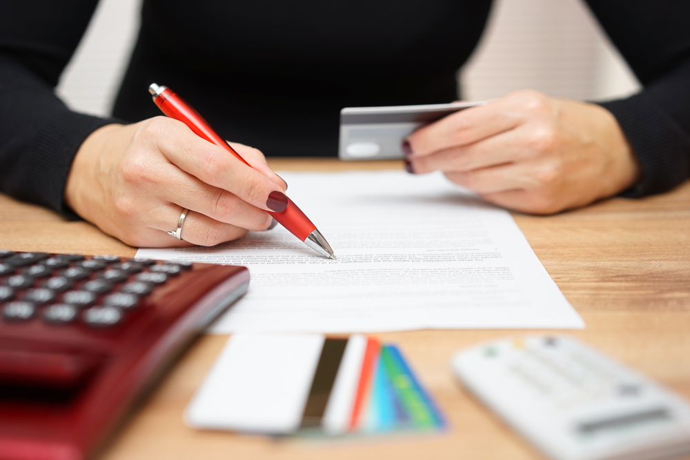 woman holding a red pen and filling up bank record form