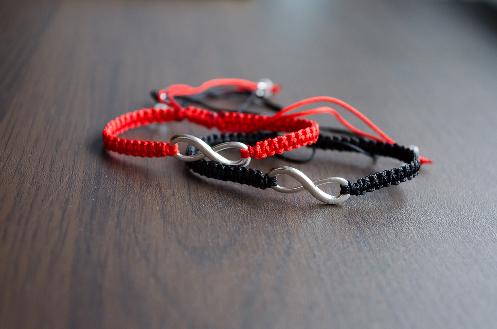 A pair of red and black bracelets with infinity metal